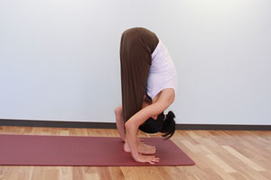 10.息を吐きながらもう一方の脚も前に進めて両足揃え、腰から上体を前に倒し、3と同様に手のひらを床につけ、手と足の指先を横一線にそろえ前屈。